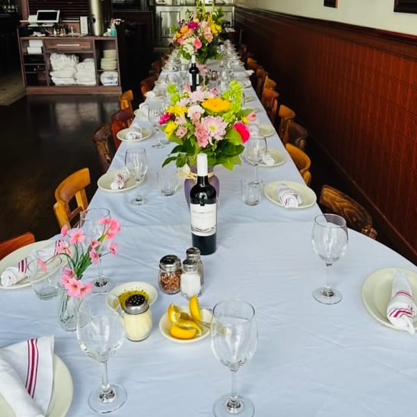 Long dining table set for a private event at Nick's Italian restaurant, adorned with flowers and wine.