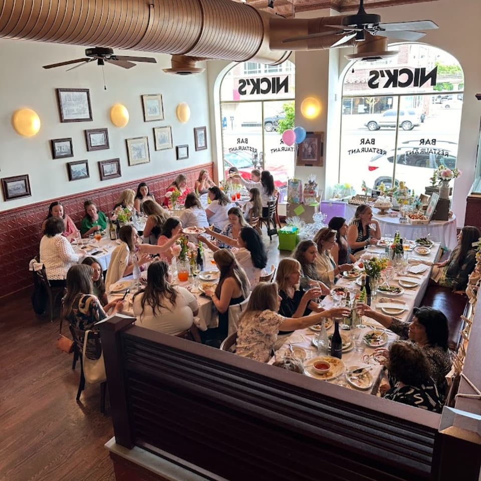 Women gather for a celebration at Nick's Italian restaurant, with tables set for dining and gifts.