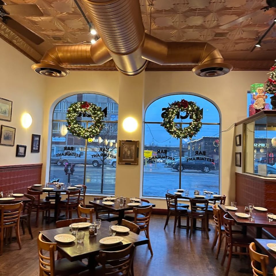 Interior of Nick's Italian restaurant with set tables, arched windows, and holiday wreaths.